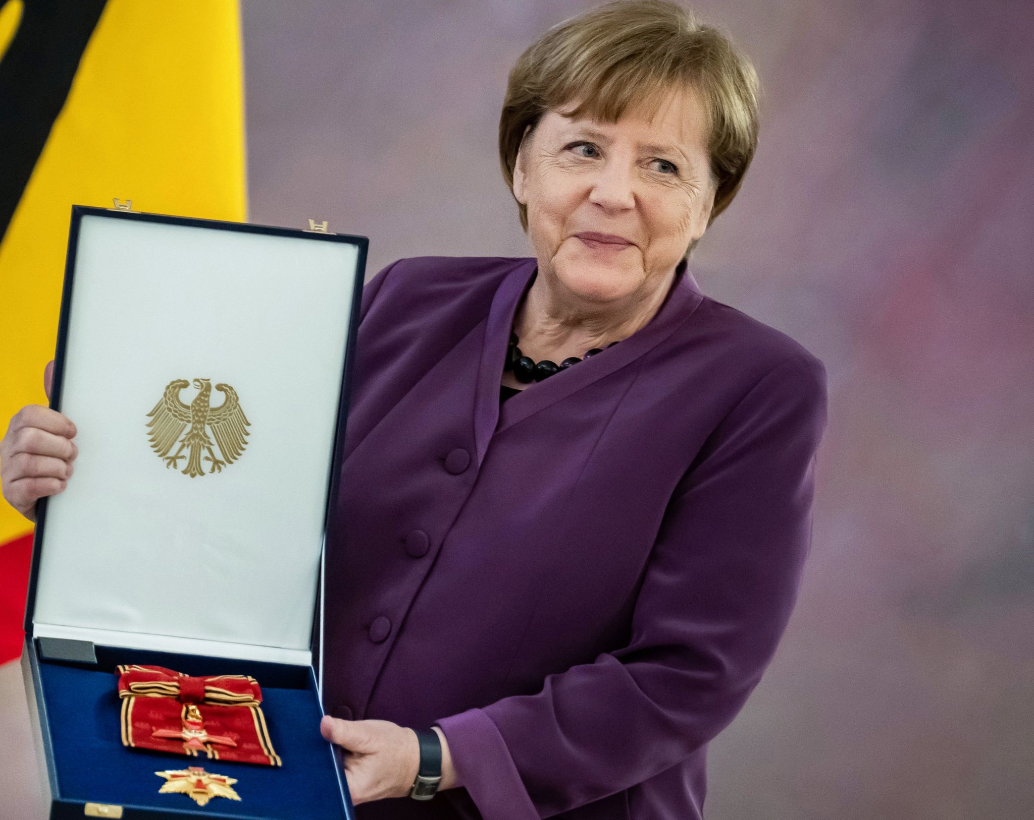 Die ehemalige Kanzlerin Angela Merkel hält das Großkreuz des Verdienstordens der Bundesrepublik Deutschland in den Händen. Foto: Michael Kappeler/dpa
