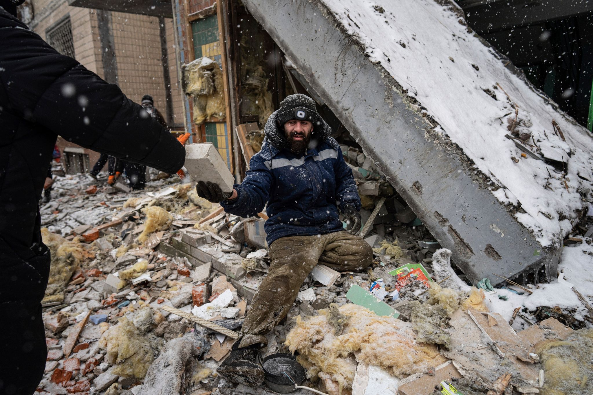 Ein Freiwilliger räumt die Trümmer eines Wohnhauses weg, das bei einem russischen Angriff schwer beschädigt wurde. Foto: Evgeniy Maloletka/AP/dpa