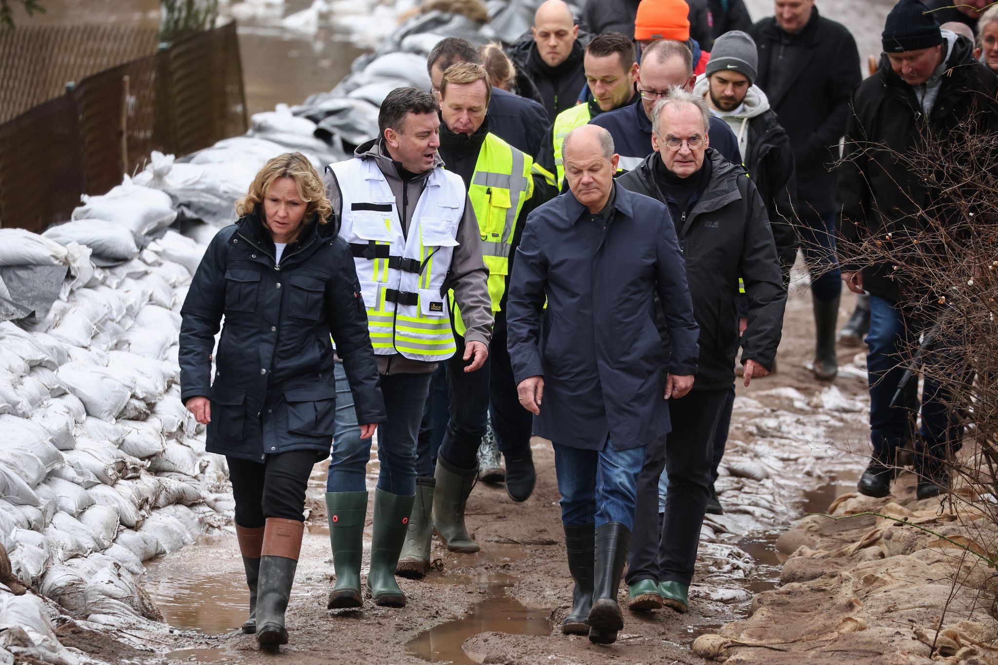 Bundeskanzler Olaf Scholz (vorne rechts) trägt bei seinem Besuch im Hochwassergebiet in Sangerhausen Gummistiefel. Foto: Jan Woitas/dpa