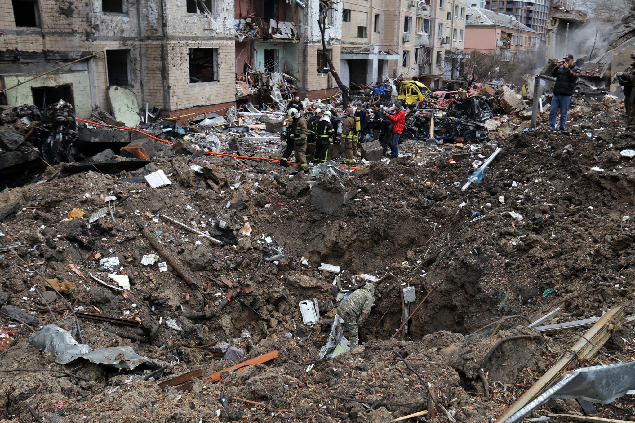 Rettungskräfte stehen neben einem Krater in der Nähe beschädigter Wohngebäude nach einem russischen Raketenangriff. Foto: -/Ukrinform/dpa