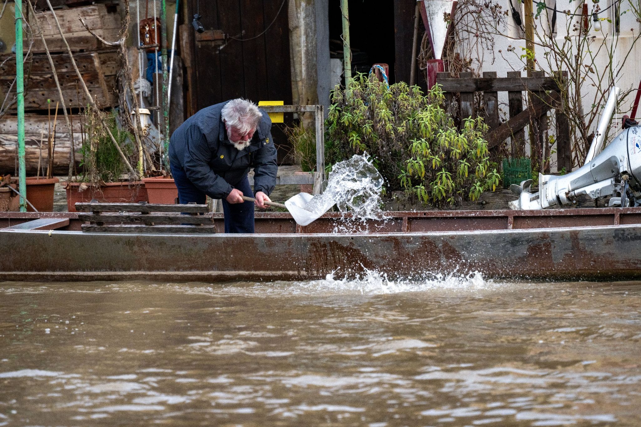 Ein Anwohner an der Fischerei in Bamberg schöpft Wasser aus einem Boot. Foto: Pia Bayer/dpa